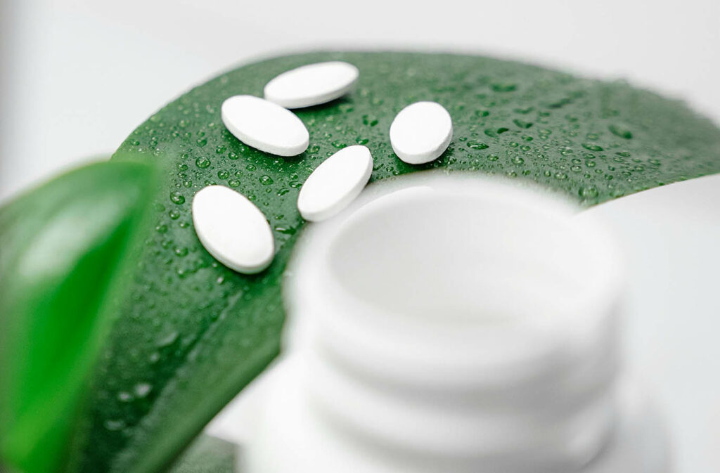 White pills on a green leaf, close-up photo